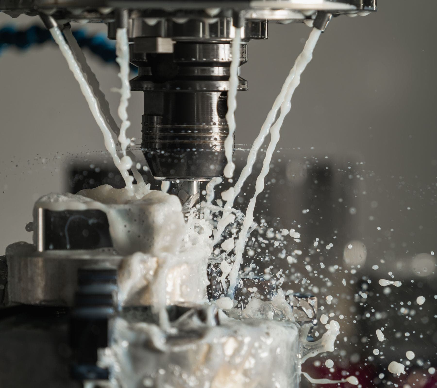 Five-axis machining centre cutting an aerospace bracket under coolant
